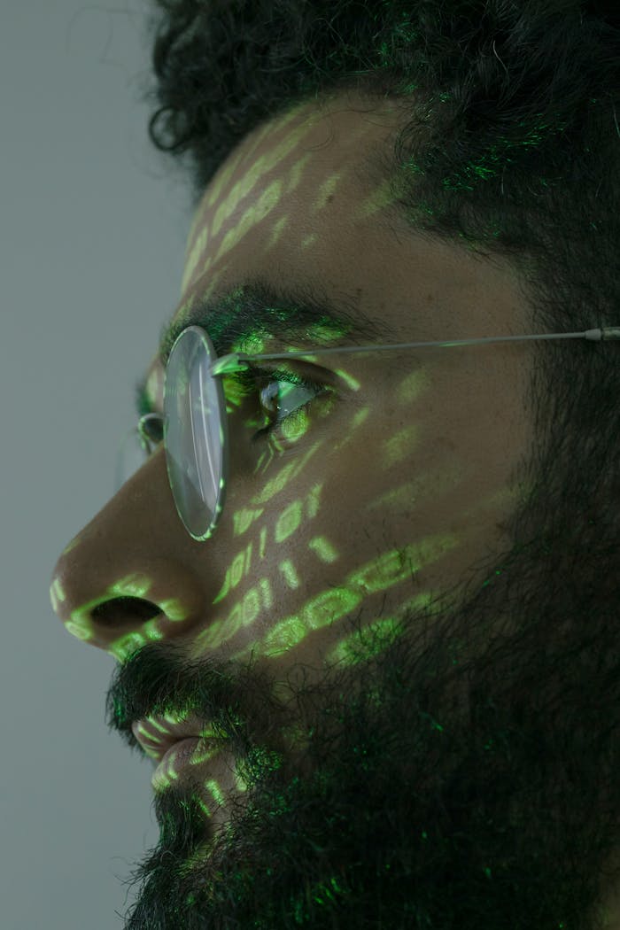 Services Close-up portrait of a man with glasses, digital code projected on his face.